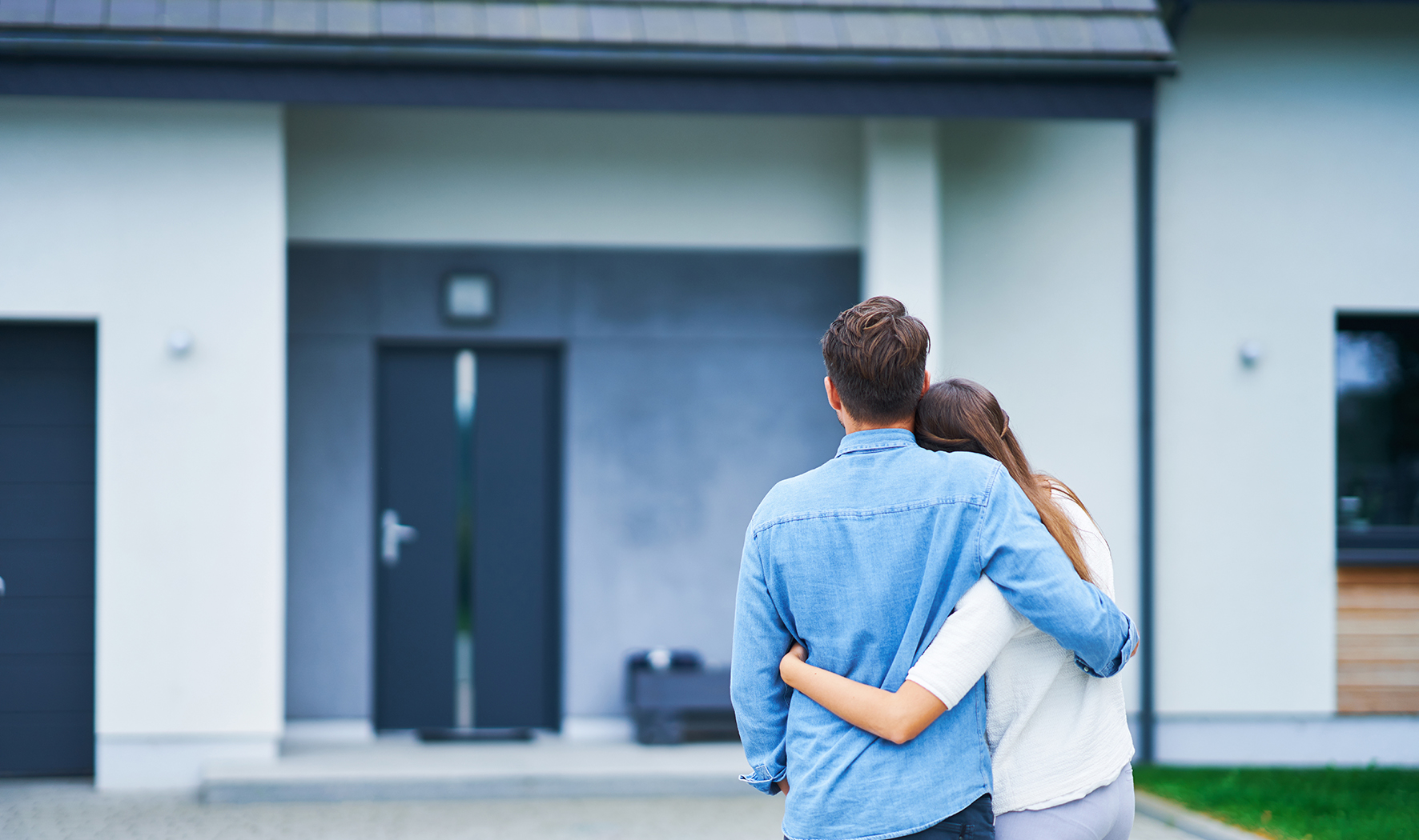 Couple in front of one-family house in modern residential area